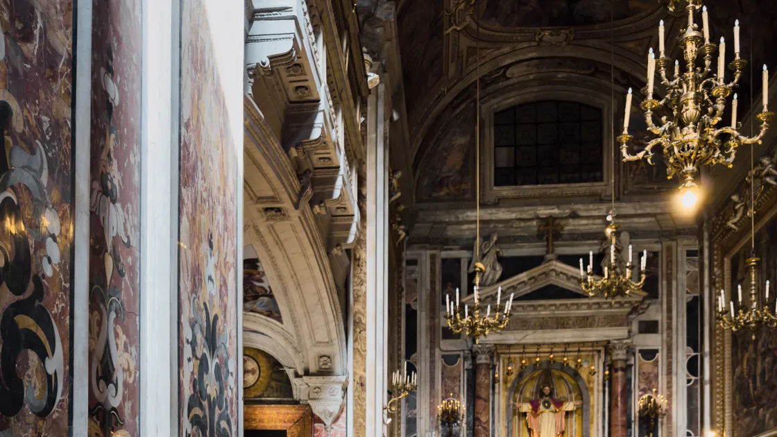 Altar dourado de uma igreja católica antiga, com castiçais acesos e imagem sacra ao fundo