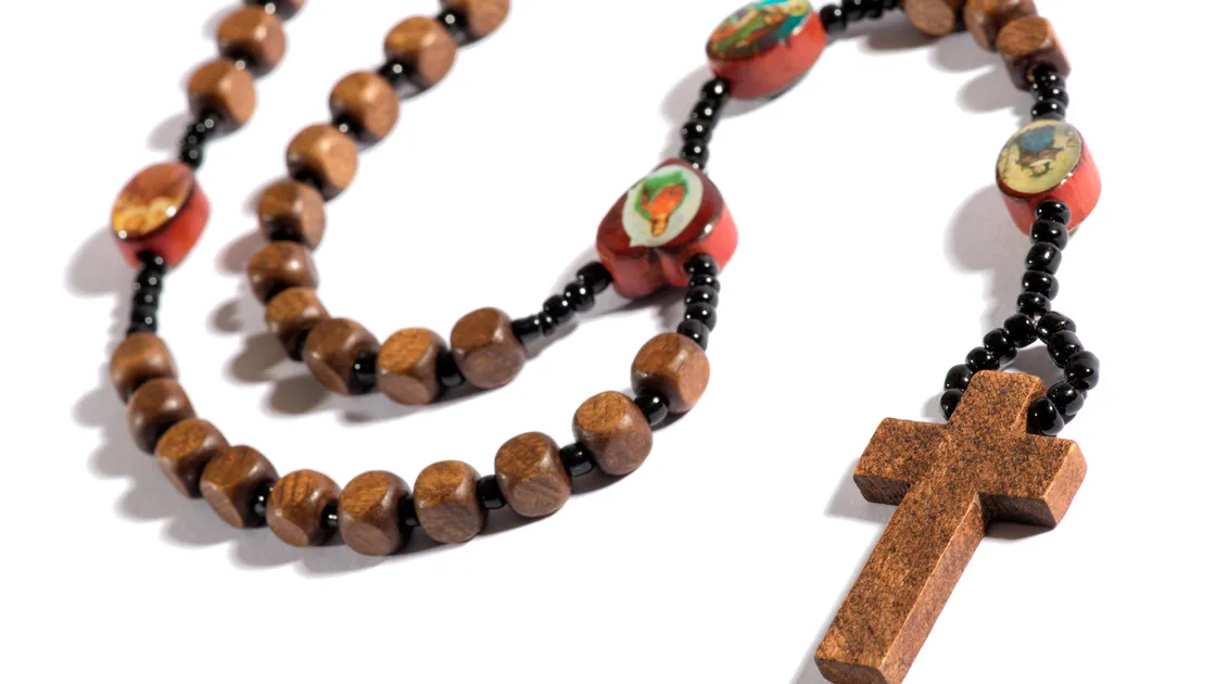 Terço de madeira com contas escuras, medalhões vermelhos com imagens de santos e crucifixo, sobre fundo branco